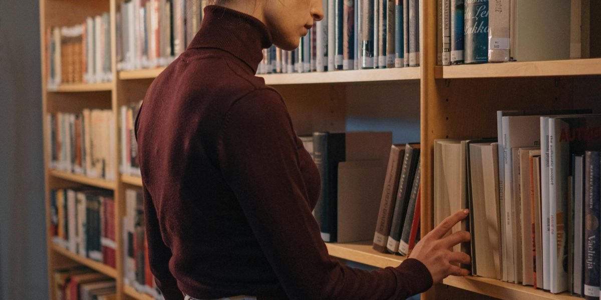A reader surrounded by shelves of old books, reflecting the journey into different eras that classic novels offer.