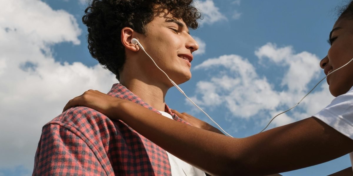 Two young friends sharing headphones, reflecting a moment of connection and shared interests, similar to the bond in 'Eleanor & Park'.
